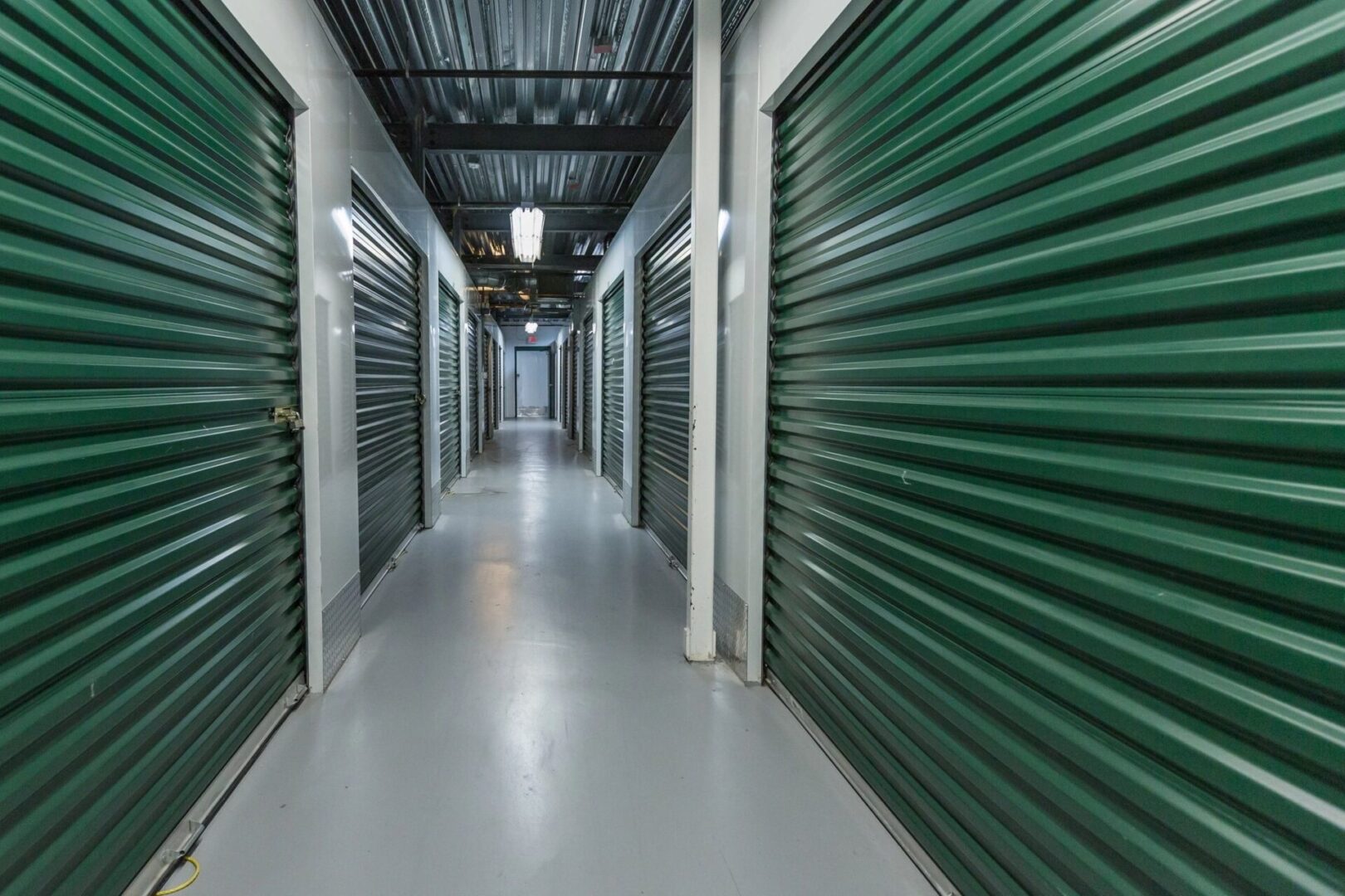 A hallway with many green doors and white walls.